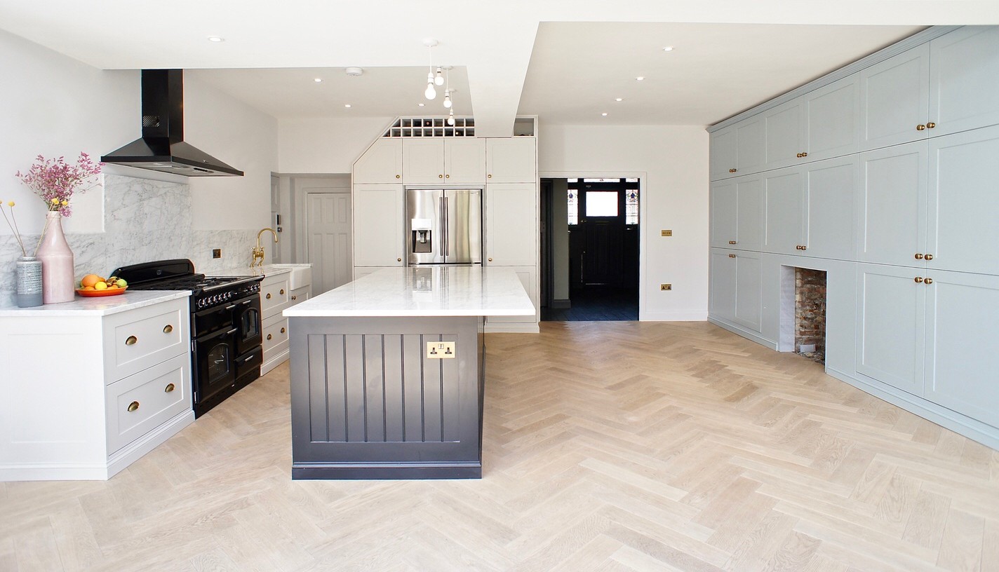 pale shaker style kitchen with a marble topped island and range cooker