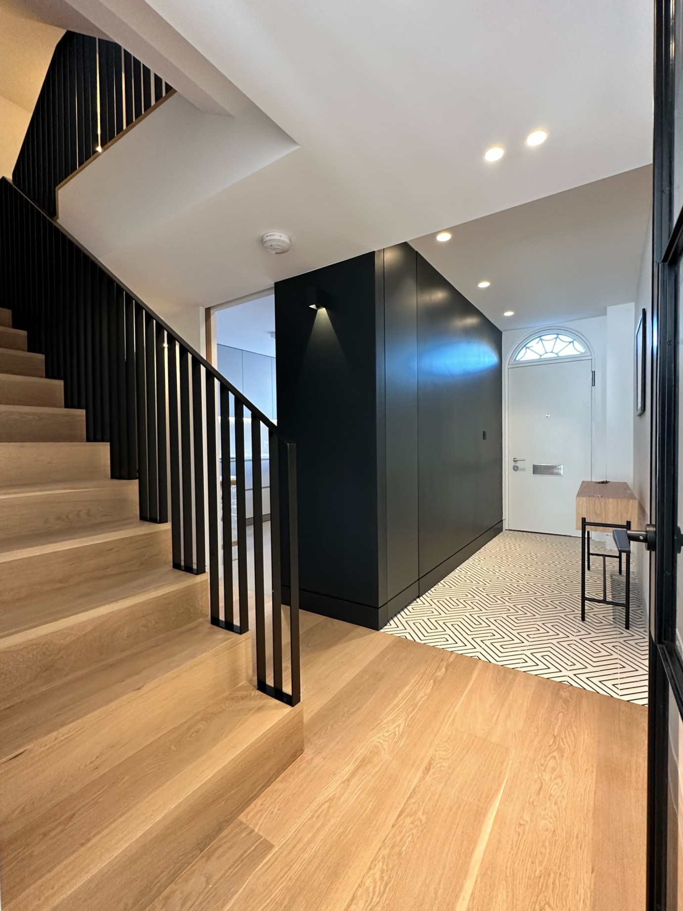 modern black hallway storage with oak stairs and black metal banister